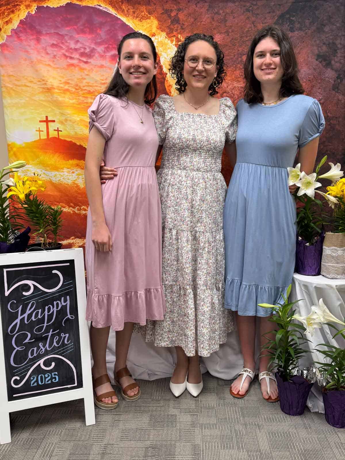 three girls posing in front of an Easter backdrop with an Easter sign.