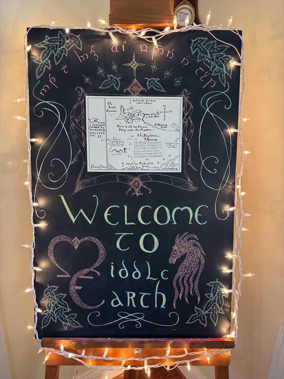 large chalk sign saying "Welcome to Middle-earth" surrounded with lights.